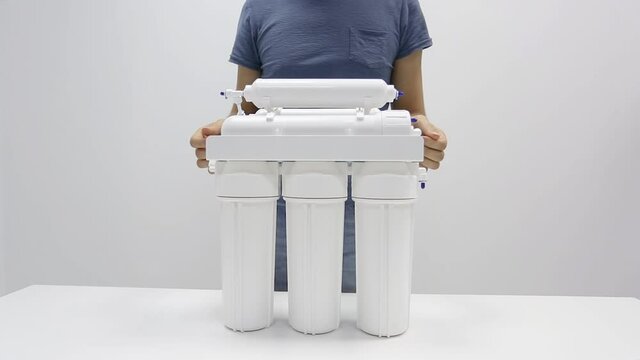 Male plumber hands adjust household reverse osmosis water filter