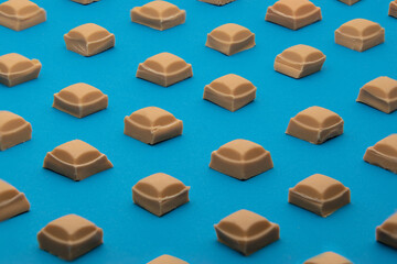 Caramel Chocolate squares against a blue background. Geometric, abstract repeating pattern