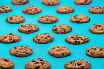 Delicious chocolate chip cookies against a teal background, geometric, repeating pattern