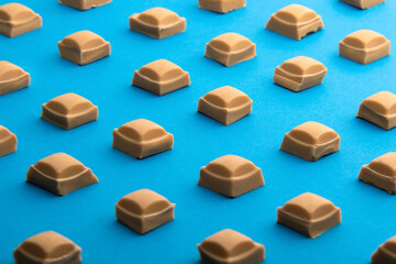 Isometric view of Caramel Chocolate squares against a blue background. 