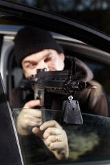 Fototapeta na wymiar Man with assault carbine waiting for his wictim inside car