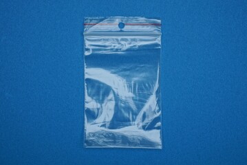 one small transparent empty plastic cellophane bag lies on a blue table