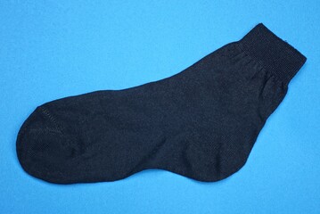 one black fabric sock lies on a blue table