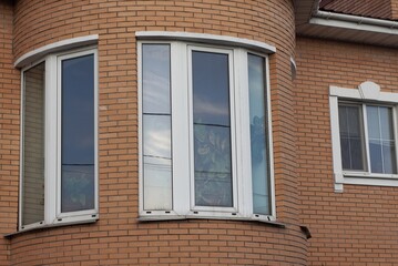 Fototapeta na wymiar two big white windows on the brown brick wall of the building