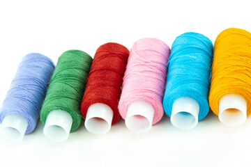 horizontal row of multi-colored threads in skeins of lilac, green, red and pink on a white background