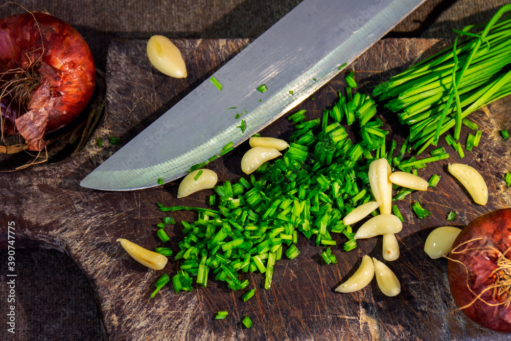 Canvas Prints High angle shot of sliced onion chives, garlic, and onions on a wooden chopping board