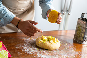 hands of a man in a kitchen, putting orange juice in a bread dough