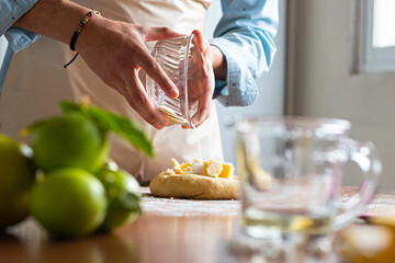 hands a man, placing flour in a dough to make bread on top of a wooden table