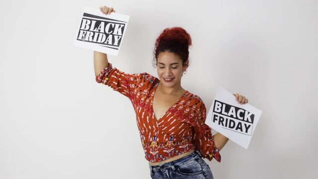 Very happy girl smiling dancing with two Black Friday posters in her hands. Young woman with white skin and curly red hair