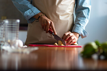 hands of a man cutting butter on top of a wooden table
