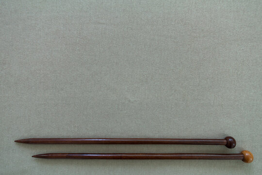 Wooden knitting needles on beige background copy space.