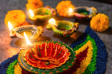 Close up clay lit light a fire already on Diya or oil lamp with flowers on concrete background,...