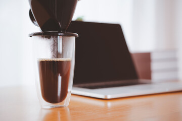 Unrecognizable man making a hand craft dripping coffee on the wooden table in the office during a break. 