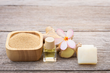 Ginger rhizome with powder, ginger soap and glass bottle of ginger essential oil extract isolated on wood table background.