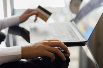 Business woman hand hold credit card and using wireless mouse, work on laptop computer for online shopping and payment at home office. e banking, e commerce concept. 