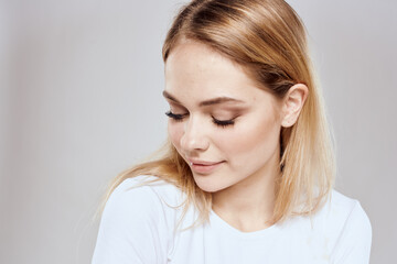 Cheerful blonde woman in white t-shirt cropped view light background