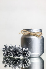 New's Year's decoration. DIY. New Year's candle of silver color with their own hands. Close-up of a silver candle and fir cones. New Year's image. High quality photo