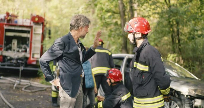 Skinny mature man telling fireman about car crash