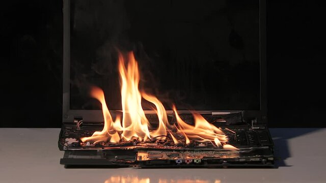 Laptop burning in flames on a desk, fire hazard. losing valuable data, 60 fps