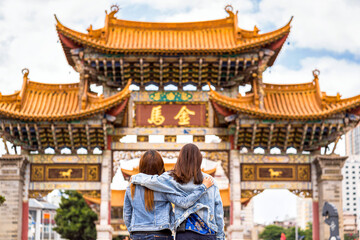 back side of Three asian happiness women walking and sightseeing together when travelling over the Jinbi square, Kunming, China, travel and tourism with friendship concept,Chinese Text is Golden Horse