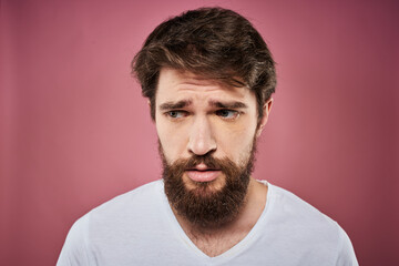 Obraz premium Emotional bearded man in white T-shirt discontent pink background