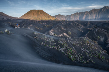 Bromo National Park, East Java, Indonesia - October 16, 2020 : Tengger man riding his horse in the distance, on the black sand savanna of Mt Bromo