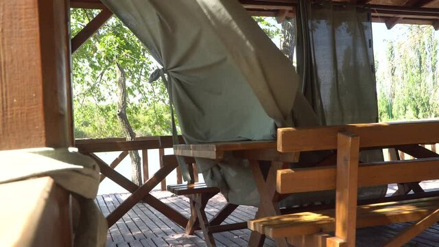 Resort restaurant by the lake on a sunny autumn day. Gray linen curtains flutter in the wind on the terrace