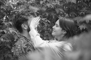 Black and white bright picture. Lovely young couple having fun. Girlfriend closes his eyes playing hide and seek. Beautiful casual woman and curly man with beard. Tenderness in relationships. 