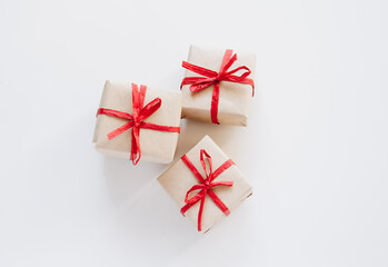 Top view on gift boxes made from craft paper with red ribbon on white background.