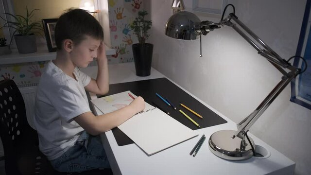 a European child draws with colored pencils at the table