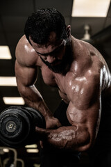 Fototapeta na wymiar strong man athlete with beard training his biceps muscle using heavy weight dumbbell in fitness gym