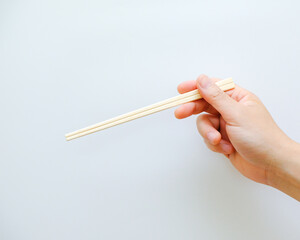 hand holding chopsticks isolated on white background, copy space template for banner, kitchen equipment, a product from nature
