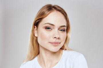 Cheerful blonde woman in white t-shirt cropped view light background