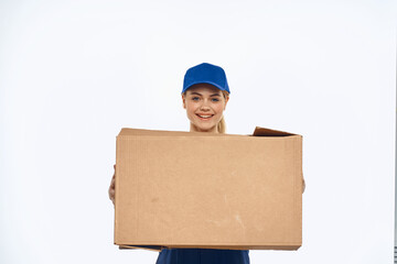 A woman in a working uniform with a box in the hands of a delivery service delivery service light background