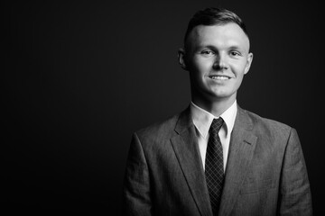 Young businessman wearing suit against gray background