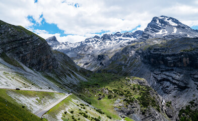Fototapeta na wymiar Summer Stelvio pass with alpine road and snow on slope. Panoramic view of the over the alps between Lombardy and Trentino. Color image. Italian mountains.