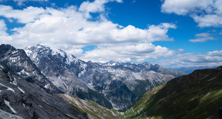 Fototapeta na wymiar Summer Stelvio pass with alpine road and snow on slope. Panoramic view of the over the alps between Lombardy and Trentino. Color image. Italian mountains.