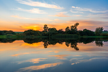 View of the lake at sunset with the reflection of the forest on the shore