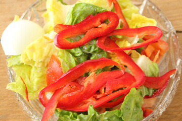 a glass bowl with fresh lettuce, bell pepper and egg