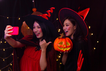 Two Asian women wore witch costumes at Halloween festivities.