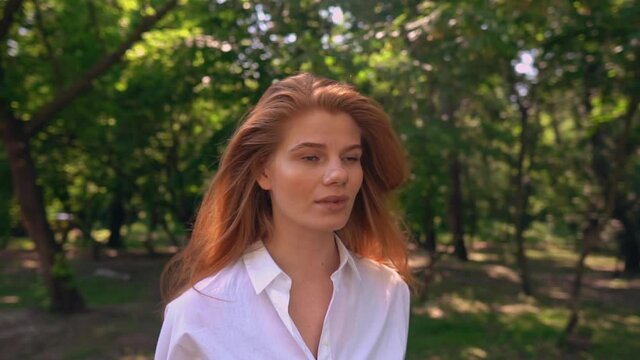 camera move around face young woman with beautiful red long hair lifestyle in summer season outdoors