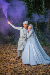 Wedding photo shooting. The bride and groom with smoke bombs on the background of trees