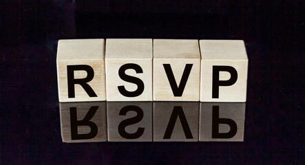 abbreviation rsvp request for a response from an invited person in wooden blocks on a black mirrored background with reflection