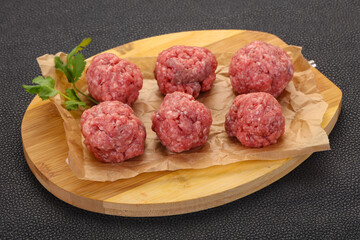 Raw meatball over wooden background