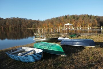 Wooden boats standing on bank of lake in autumn scenery. Wooden piers by the lake. Kashubia, Poland