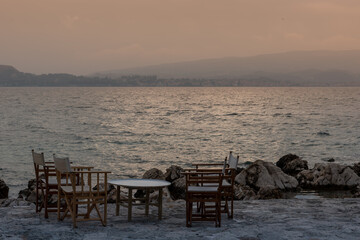 Fototapeta na wymiar Small tables of a restaurant by the Greek sea