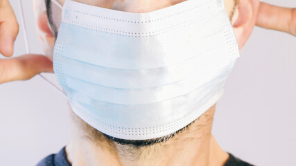 Close-up of a man's face putting on his protective mask. Concept of protection against coronavirus