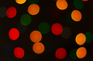 Multicolored circular bokeh lights on dark black background. Christmas holiday lights
