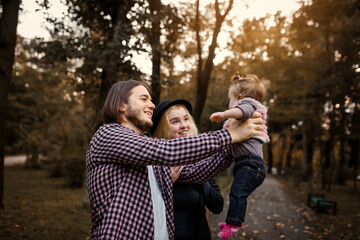 Fototapeta premium Beautiful young mother holds her baby in her hands and father is near her.