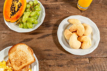 Breakfast table, top view. Toast and eggs, and a glass of orange juice. A white dish with papaya and grapes.